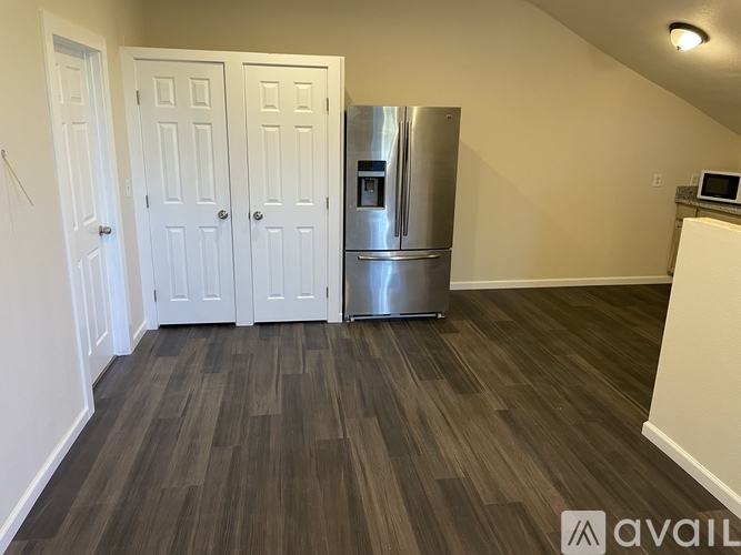 A kitchen area with a refrigerator, cabinets, and a microwave.