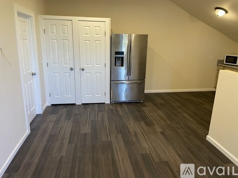 A kitchen area with a refrigerator, cabinets, and a microwave.