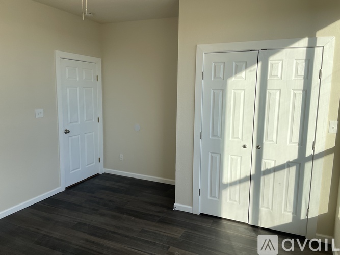 A room with a white door and a white closet door with a wood floor.