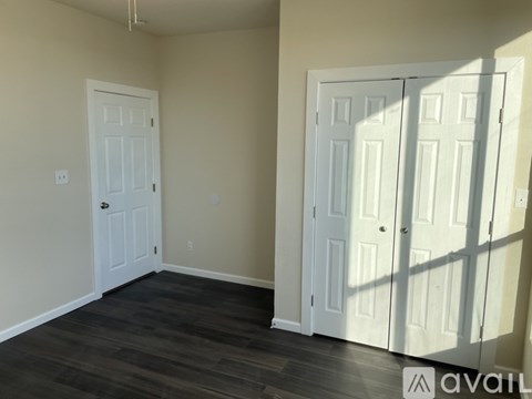 A room with a white door and a white closet door with a wood floor.