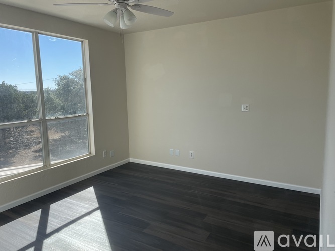 A room with a ceiling fan and a large window overlooking a field.