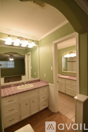 A bathroom with green walls and a vanity with a pink tile counter.