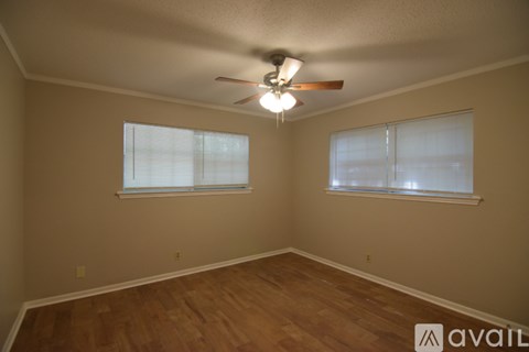 A room with a ceiling fan and two windows.