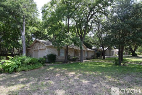 A house surrounded by trees in a grassy area.