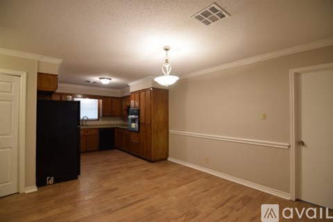 A kitchen area with wooden cabinets and a black refrigerator.