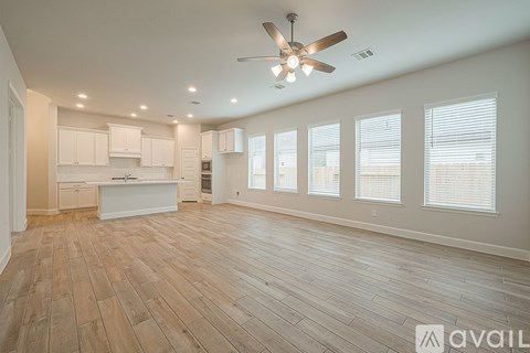A spacious room with wooden flooring and a ceiling fan.