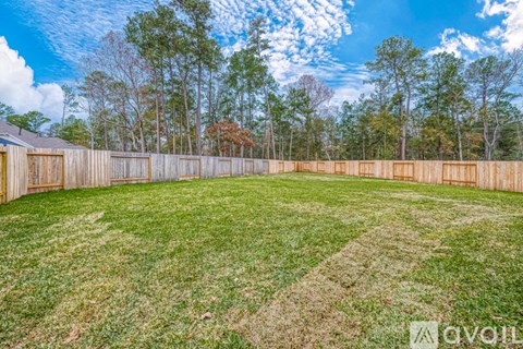 A backyard with a wooden fence and a grassy area.