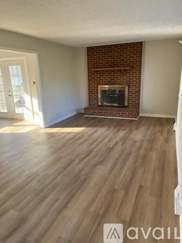 A room with a brick fireplace and wooden flooring.