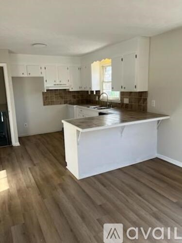 A kitchen with white cabinets and a wooden island.