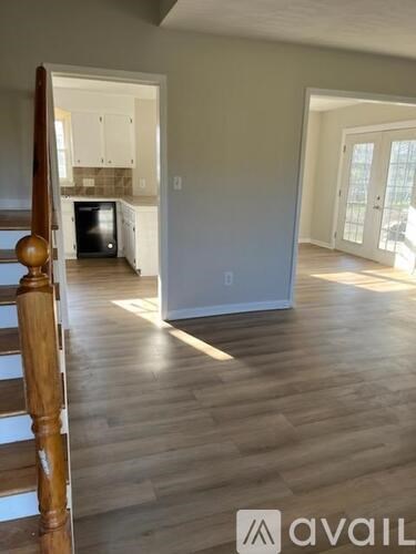 A room with wooden floors and a staircase leading to another room.