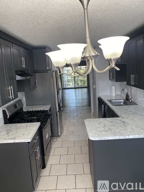 A kitchen with black cabinets and a marble countertop.