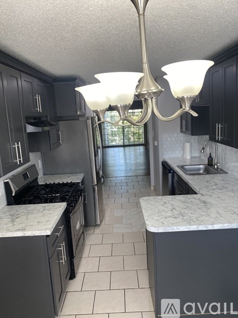 A kitchen with black cabinets and a marble countertop.