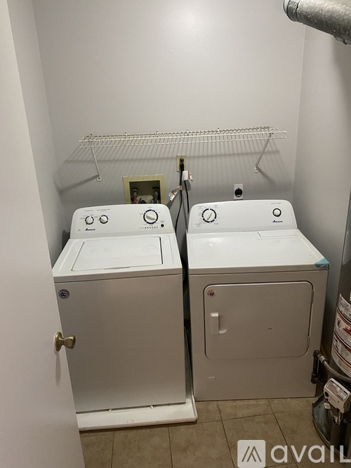A bathroom with two white toilets and a shelf above them.