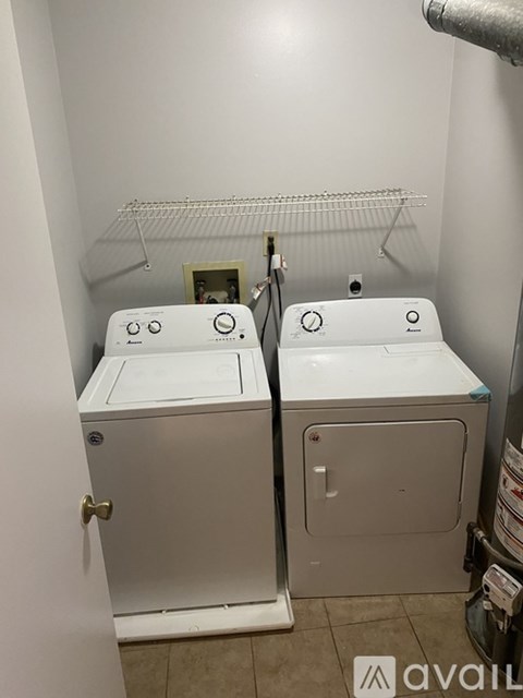 A bathroom with two white toilets and a shelf above them.