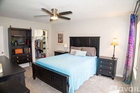 A bedroom with a bed, dresser, and a ceiling fan.