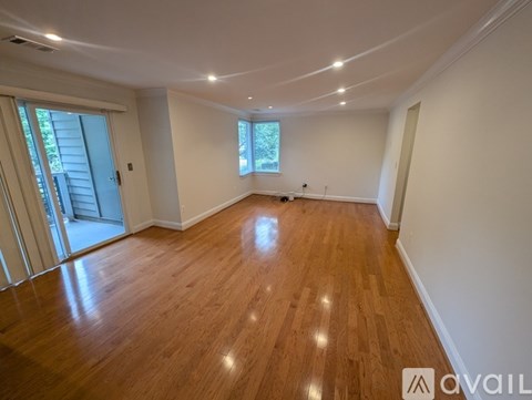 A spacious room with wooden flooring and a window.