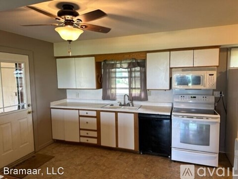 A kitchen with white cabinets and a black dishwasher.