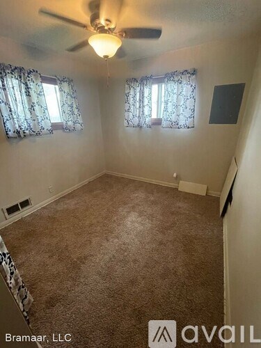A room with a carpeted floor and a ceiling fan.