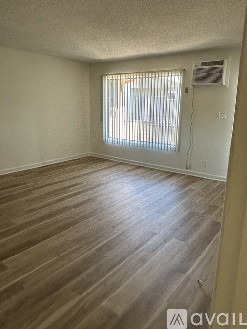 A room with wooden flooring and a window with blinds.