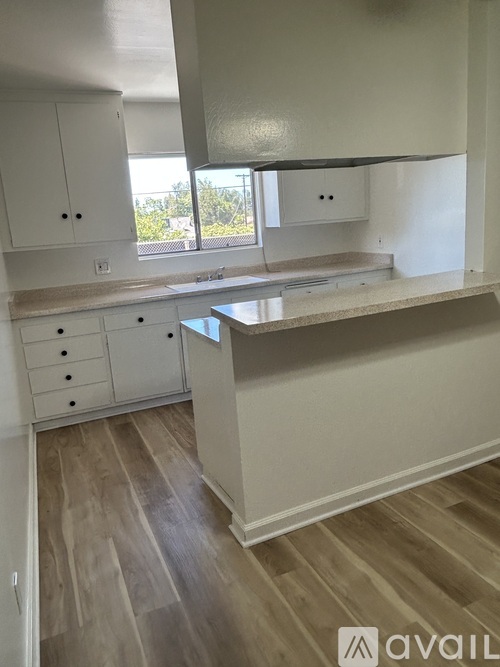 A kitchen with white cabinets and a wooden floor.