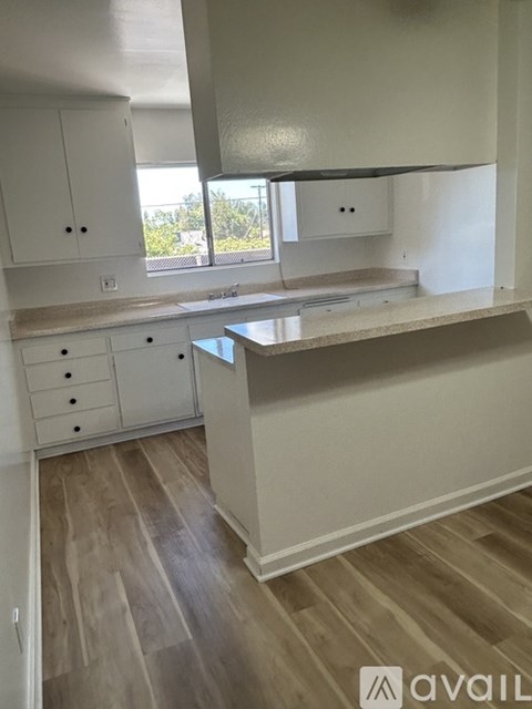 A kitchen with white cabinets and a wooden floor.