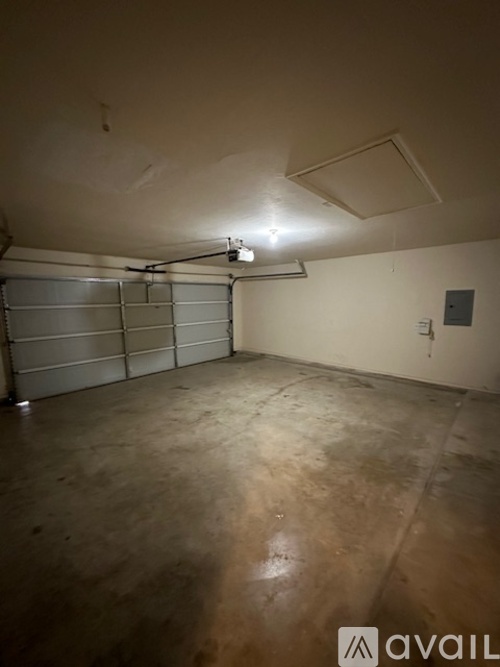 A spacious garage with a concrete floor and a metal garage door opener.