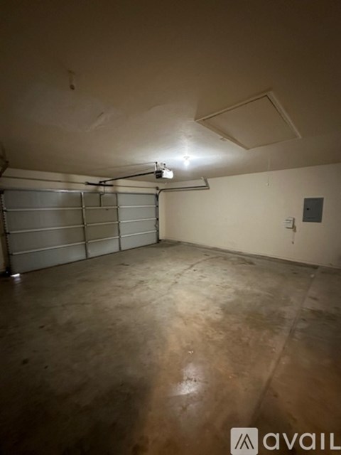 A spacious garage with a concrete floor and a metal garage door opener.