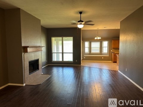 A spacious living room with a fireplace and a ceiling fan.