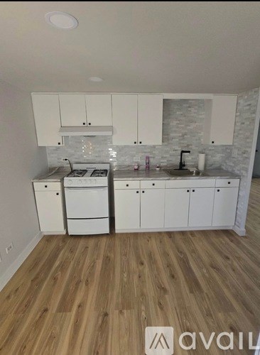 A kitchen with white cabinets and a wooden floor.