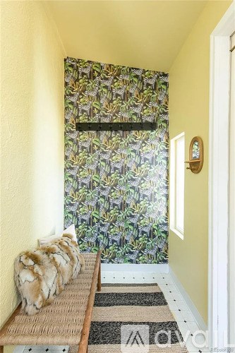 A cat is sitting on a bench in front of a window with a floral curtain.