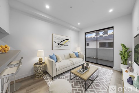 A modern living room with a white sofa, a coffee table, and a painting on the wall.