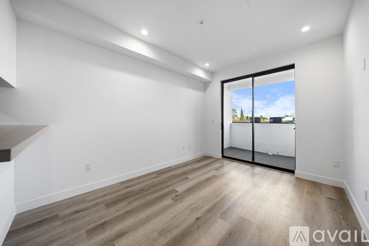 A spacious room with wooden flooring and a large window with a view of the outside.