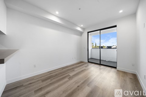 A spacious room with wooden flooring and a large window with a view of the outside.