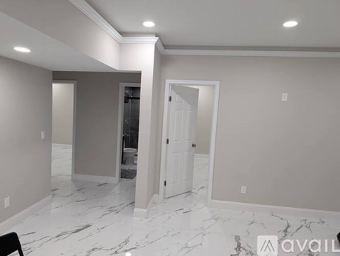 A spacious room with marble flooring and white walls.