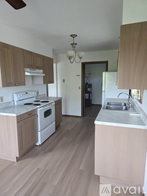A kitchen with wooden cabinets and a white stove top oven.