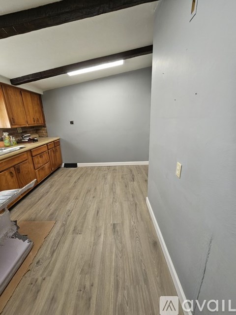 A kitchen with wooden cabinets and a grey wall.