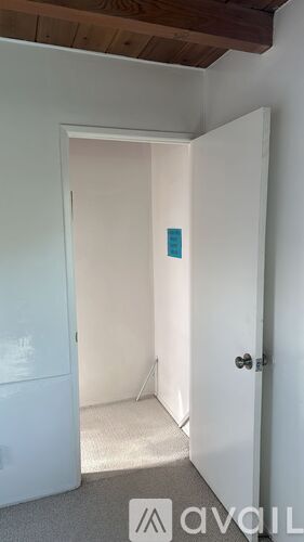 A white door with a black handle is open to a hallway.