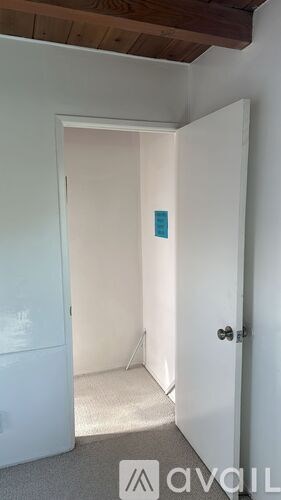A white door with a black handle is open to a hallway.