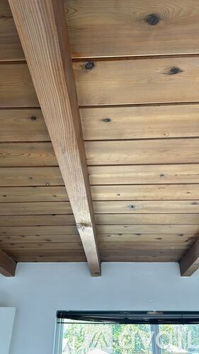 A wooden beam ceiling with a window underneath.