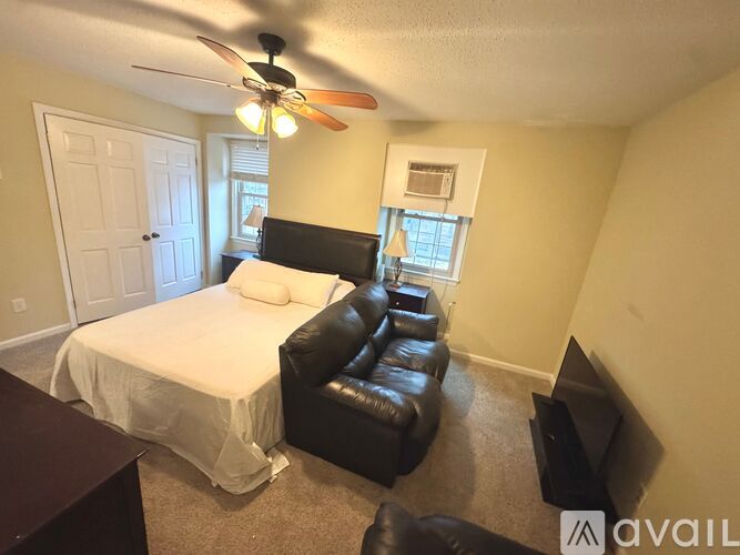 A bedroom with a bed, chair, and ceiling fan.