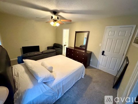 A bedroom with a bed, dresser, mirror, and a ceiling fan.