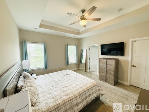 A bedroom with a bed, dresser, and television.
