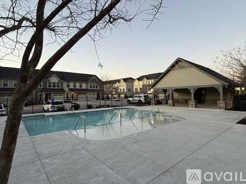 A pool surrounded by a concrete patio and a building in the background.