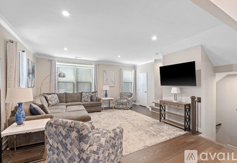 A living room with a checkered chair and a flat screen TV mounted on the wall.