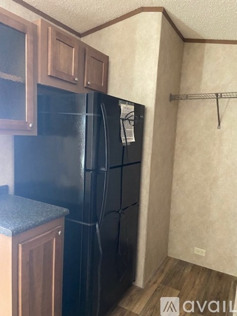 A black refrigerator in a kitchen with wooden cabinets.