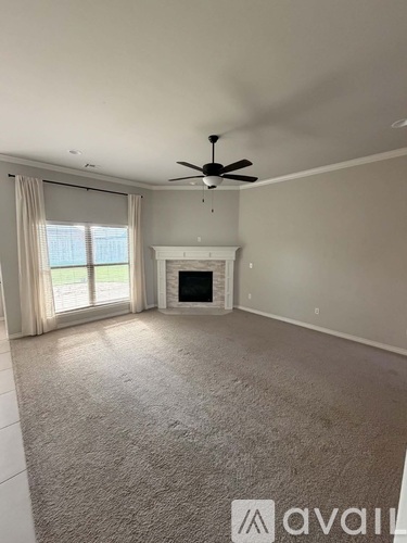 A spacious living room with a fireplace and a ceiling fan.