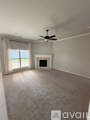 A spacious living room with a fireplace and a ceiling fan.