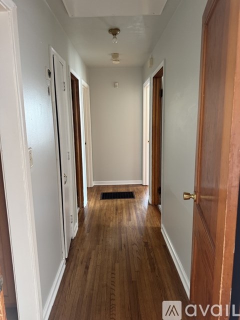 A hallway with wooden floors and white walls.
