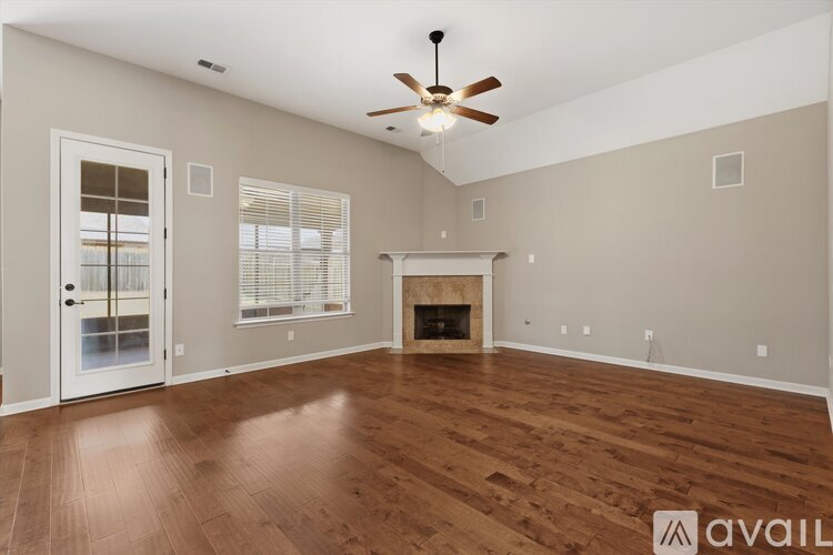A spacious living room with wood flooring and a fireplace.