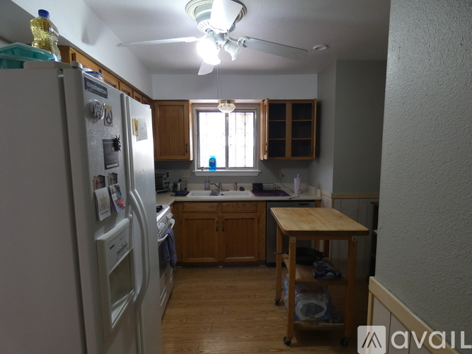 A kitchen with a white refrigerator and wooden cabinets.